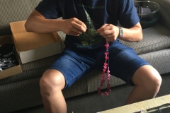 Hong Xin making leis from discarded flowers after show breakdown